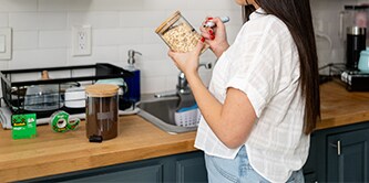 Vrouw maakt zelf labels van Scotch® Magic™ tape en plakt ze op bakjes voor etenswaren
