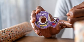 Man pakt een geschenk in met Scotch® inpaktape
