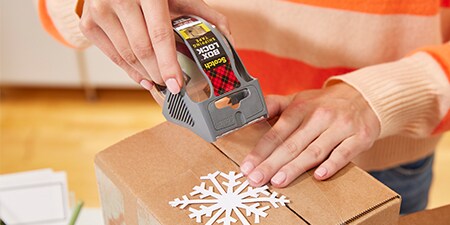 Een vakantiecadeau verzegelen in een pakket met Scotch® Box Lock™ Tape
