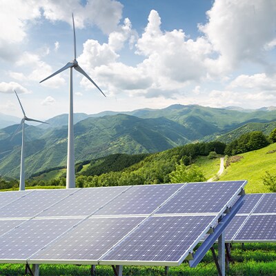 Een berglandschap met windmolens en zonnepanelen op de voorgrond.