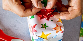 Sterren inpakpapier gebruiken en de cadeauverpakking afwerken met een lintster bovenop
