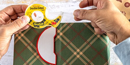 Decoraties aan een ingepakt cadeau bevestigen met Scotch® Dubbelzijdige Tape
