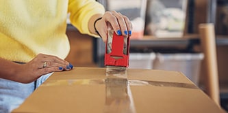 Vrouw sluit een doos af met Scotch® verpakkingstape

