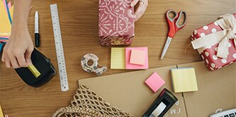 Vrouw pakt iets in met een Scotch™ Schaar, Scotch™ Tapedispenser en Scotch® Magic™ Tape
