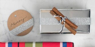 Kerstcadeaus inpakken op smaak gebracht met een kaneelstokje bovenop een cadeau bevestigd

